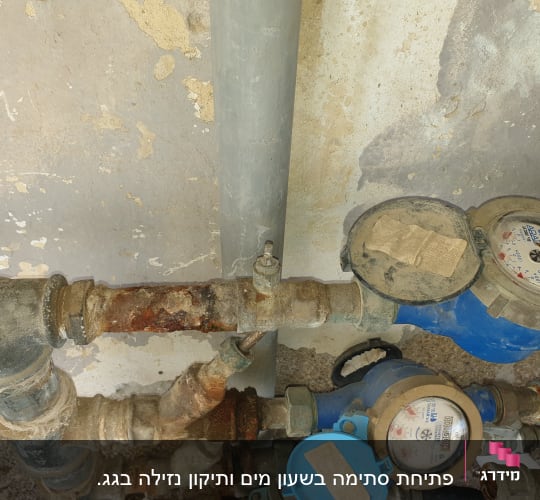 מד מים כחול עם צינורות חלודים וקירות מתקלפים